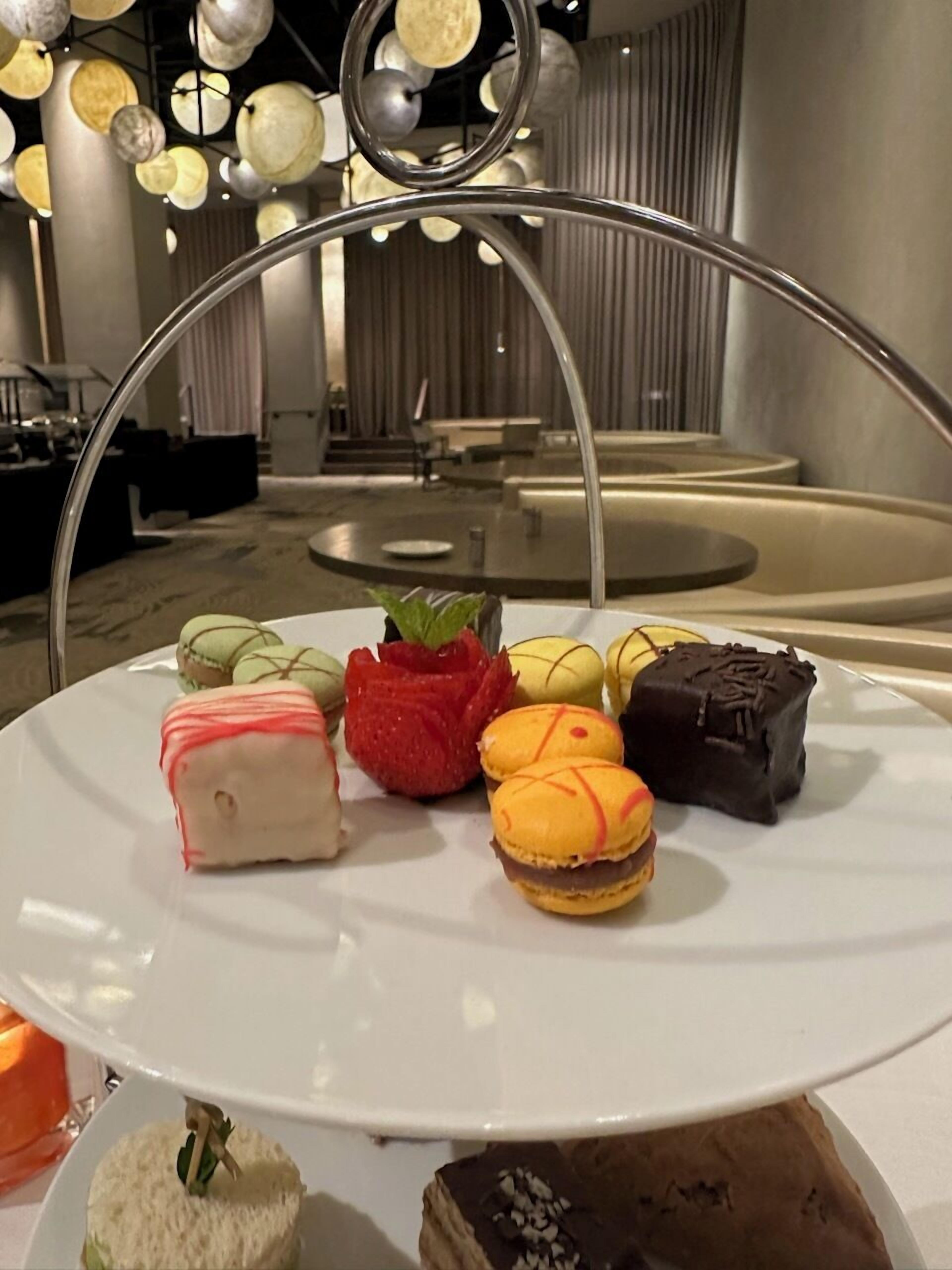 A dessert platter with various pastries on a white plate in a modern interior setting.