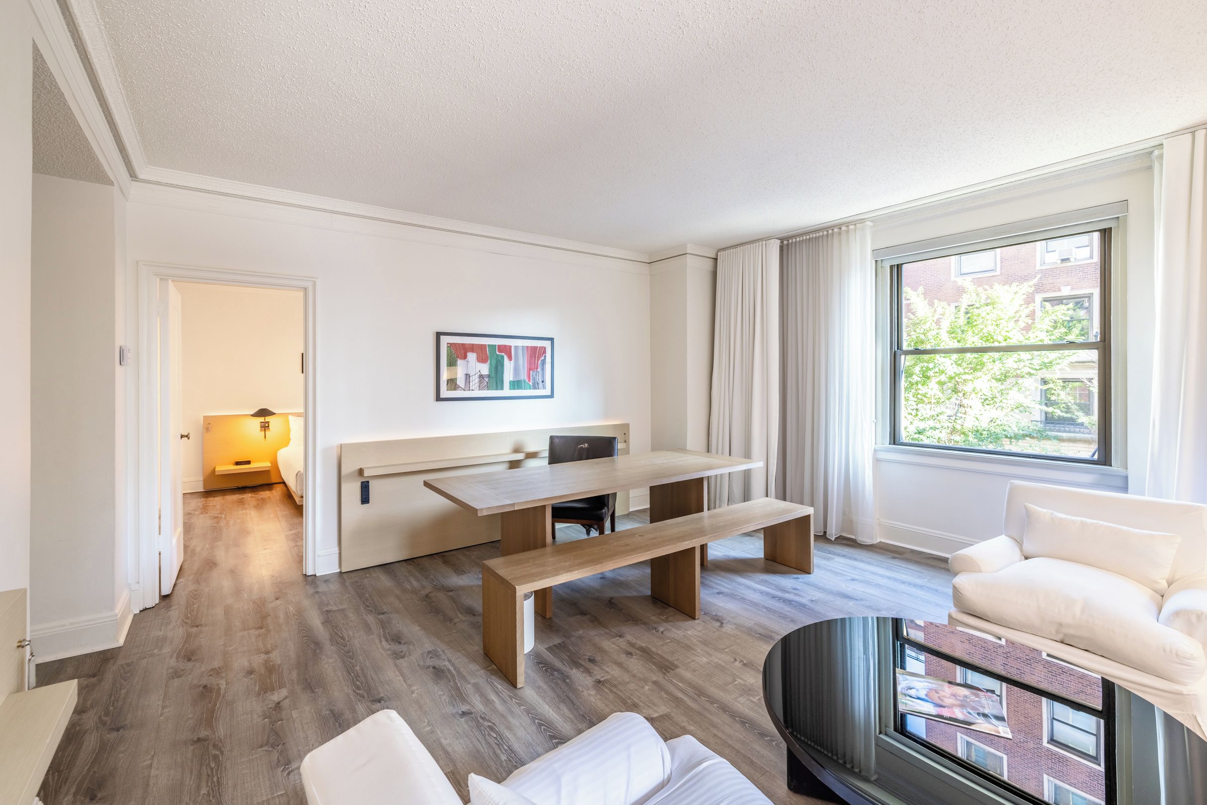 Un salon moderne avec un plancher en bois, une table à manger, un canapé et une grande fenêtre avec des rideaux.