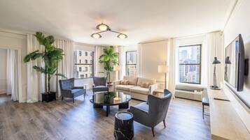 Amplia sala de estar con una mesa redonda, dos sillones, un sofá y un ventanal con vistas a la ciudad.