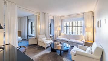 Quarto de hotel com sofá, poltronas, mesa de centro e escrivaninha.