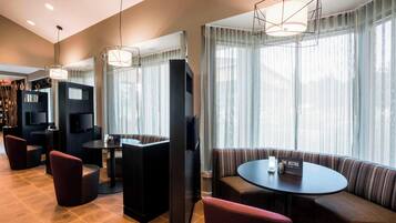 A modern hotel lobby with a seating area, a television, and a bookshelf.