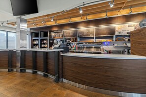 A modern bar area with a curved counter, shelves with bottles, and a menu board. - Courtyard by Marriott Chicago O'Hare (Des Plaines)
