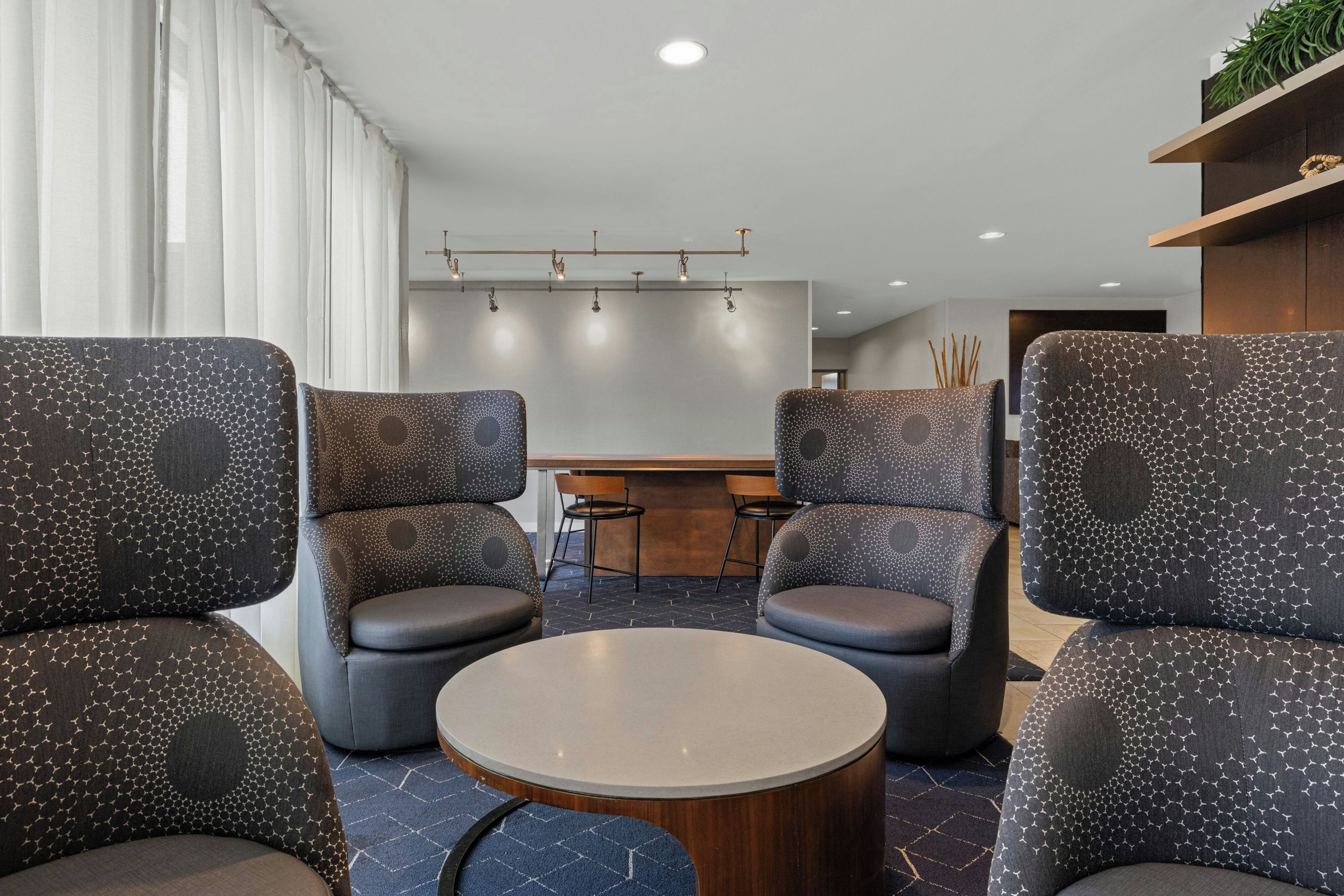 A modern interior with four armchairs, a round table, and a bar area.
