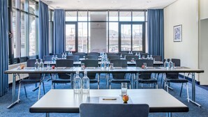Un salón de conferencias con varias mesas, sillas y botellas de agua.