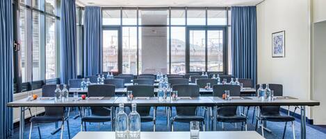 A conference room with multiple tables, chairs, and water bottles.