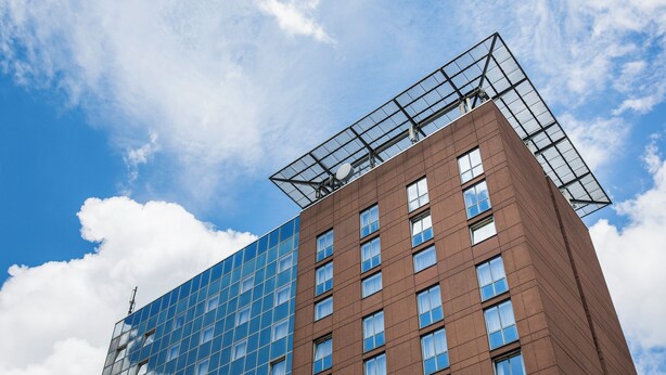Un edificio moderno con fachada de vidrio y sección de ladrillo marrón.