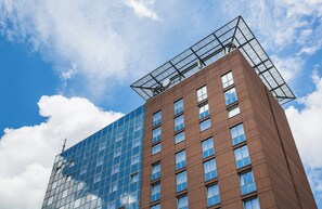 A modern building with a glass facade and a brown brick section. - Hotel Freiburg City Center by Leonardo Hotels (Freiburg im Breisgau)