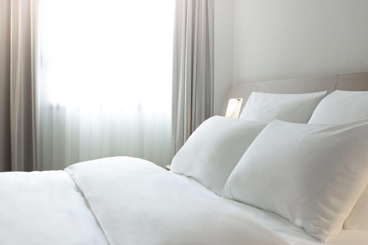 Una cama bien hecha con sábanas blancas en una habitación de hotel.