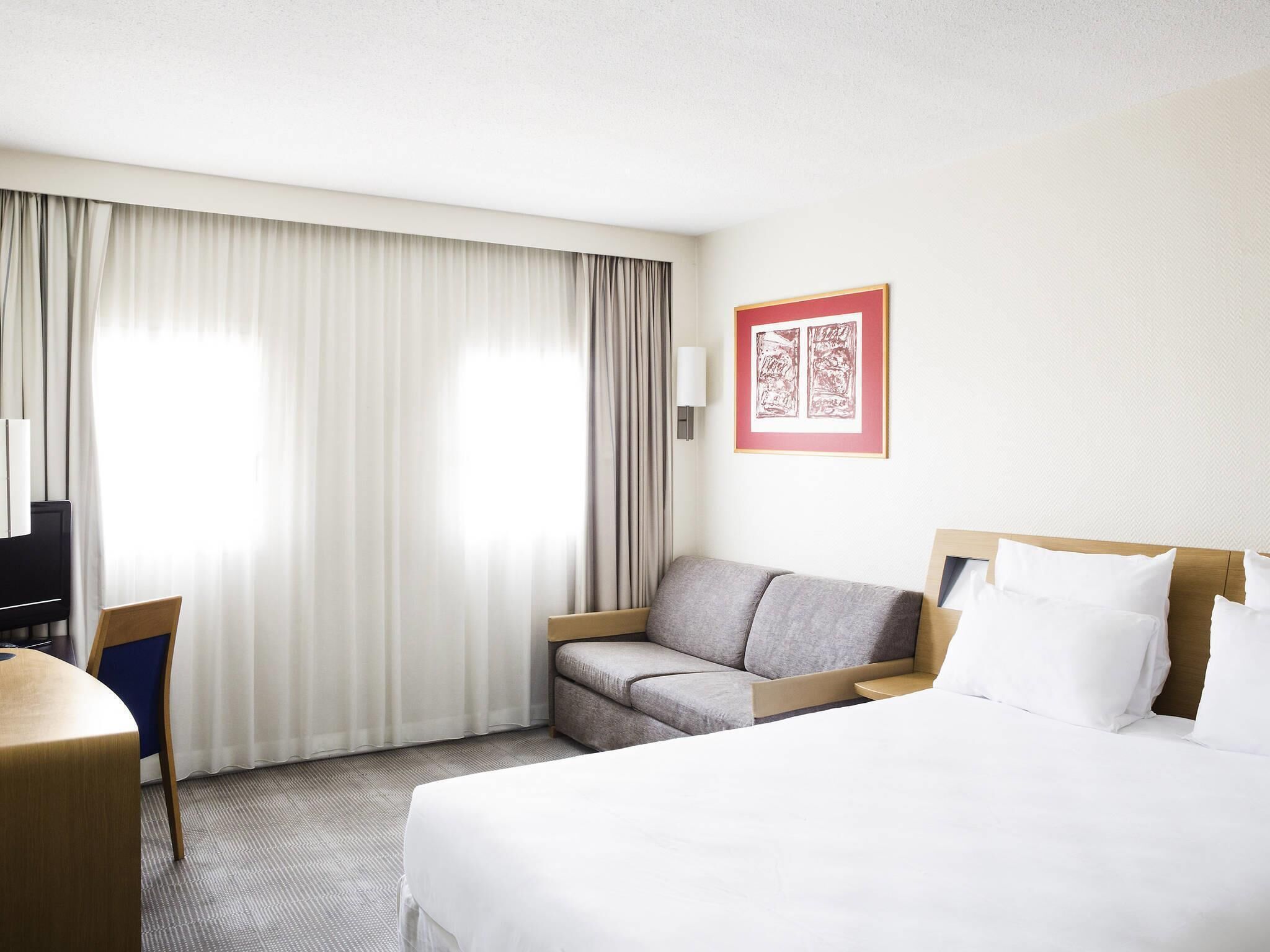 Une chambre d’hôtel avec un lit, un canapé, un bureau et une chaise.