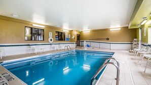An indoor swimming pool with clear water, surrounded by white chairs and a metal railing. - Quality Inn Coralville - Iowa River Landing (Coralville)