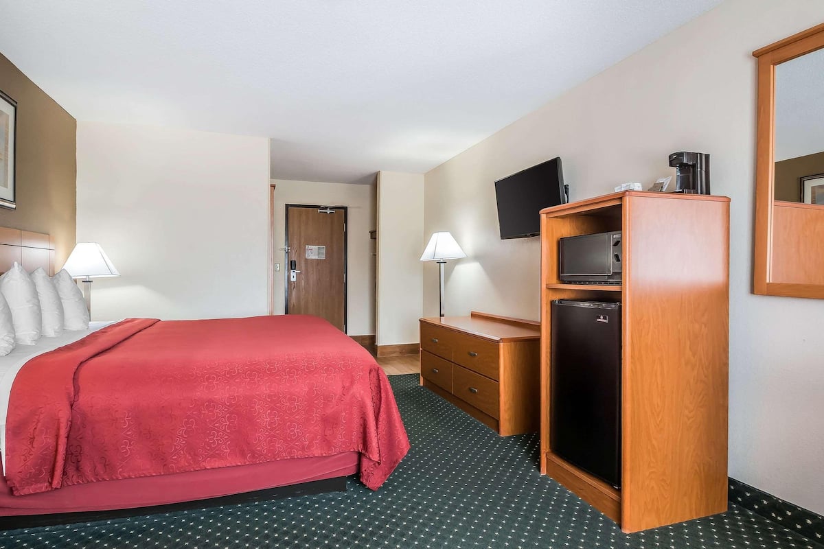 Ein Hotelzimmer mit Bett, Schreibtisch, Fernseher und Kühlschrank.