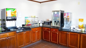 A kitchen with wooden cabinets, a microwave, a coffee maker, and a refrigerator. - Quality Inn Coralville - Iowa River Landing (Coralville)
