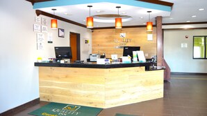 A reception area with a wooden reception desk, a computer, and a sign that reads "Quality Inn by Choice". - Quality Inn Coralville - Iowa River Landing (Coralville)
