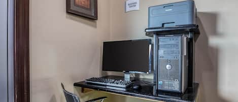 A business center desk with a desktop computer, a monitor, a keyboard, a mouse, and a printer.