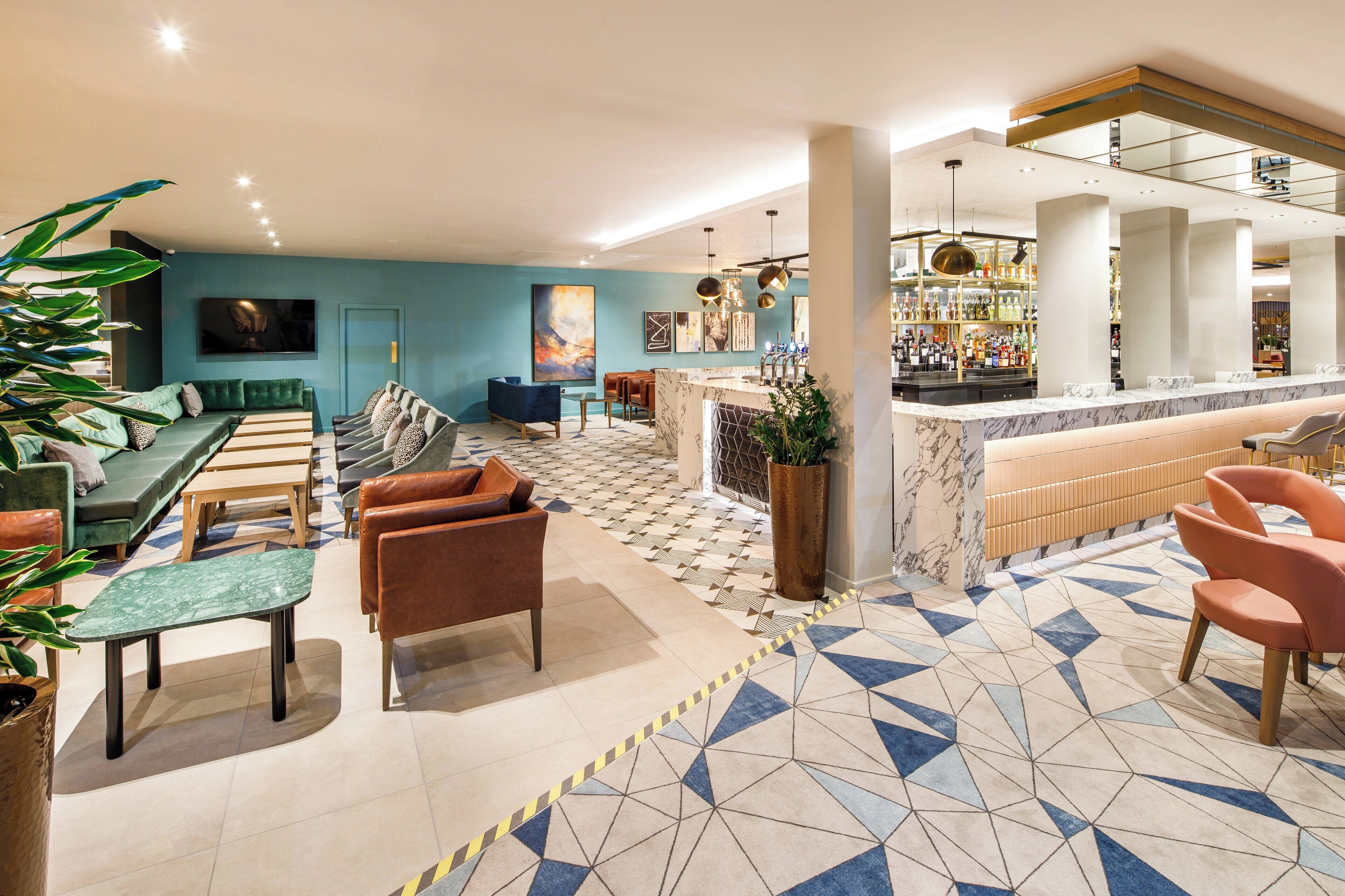A modern lounge area with a bar, seating arrangements, and a patterned floor.
