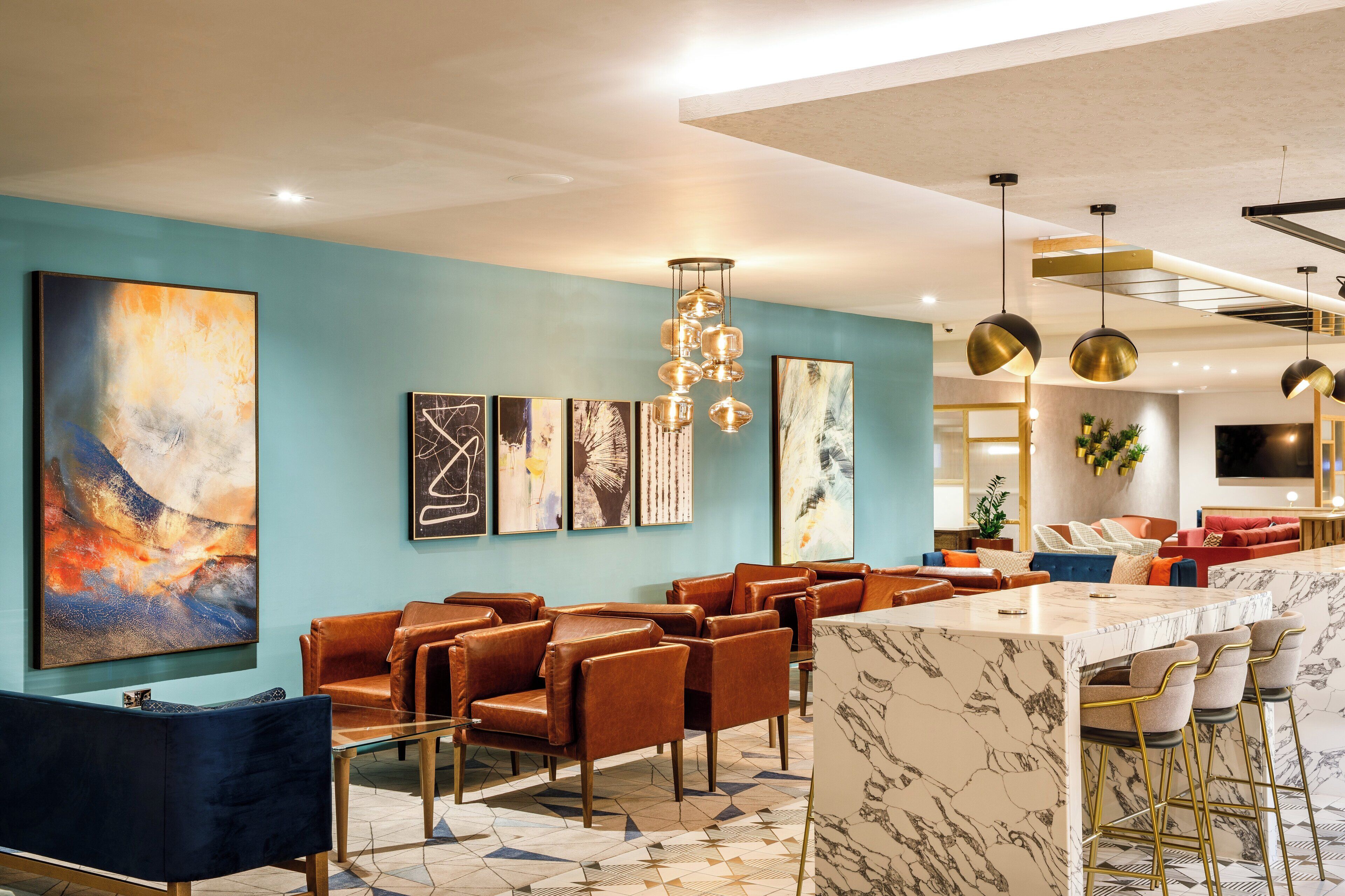 A modern lounge area with leather seating, a marble bar, and contemporary artwork on the walls.