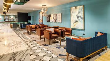 A modern lobby with a marble reception desk, leather sofas, and a geometric patterned floor.