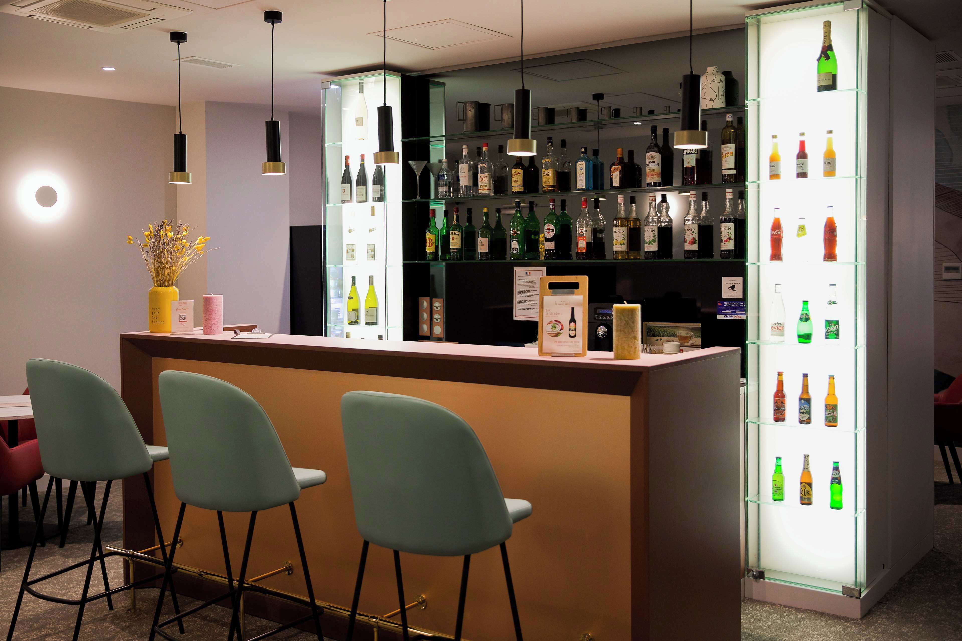 Eine Bar mit einer Theke, mehreren Flaschenregalen und drei Barhocker.