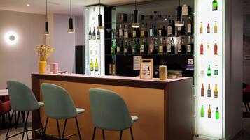 A bar area with a counter, multiple shelves of bottles, and three bar stools.