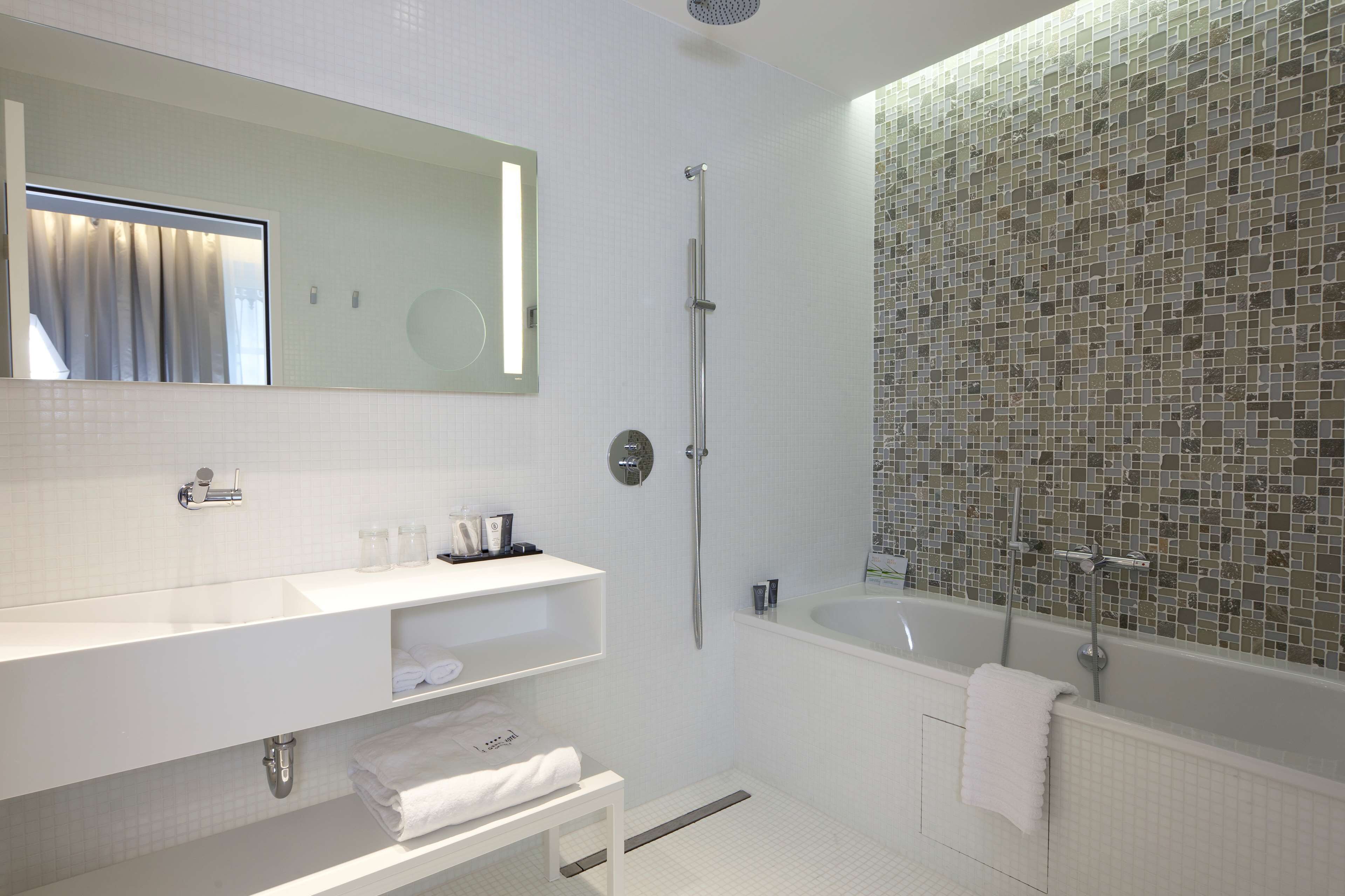 A modern bathroom with a large mirror, a white vanity, a bathtub, and a shower.