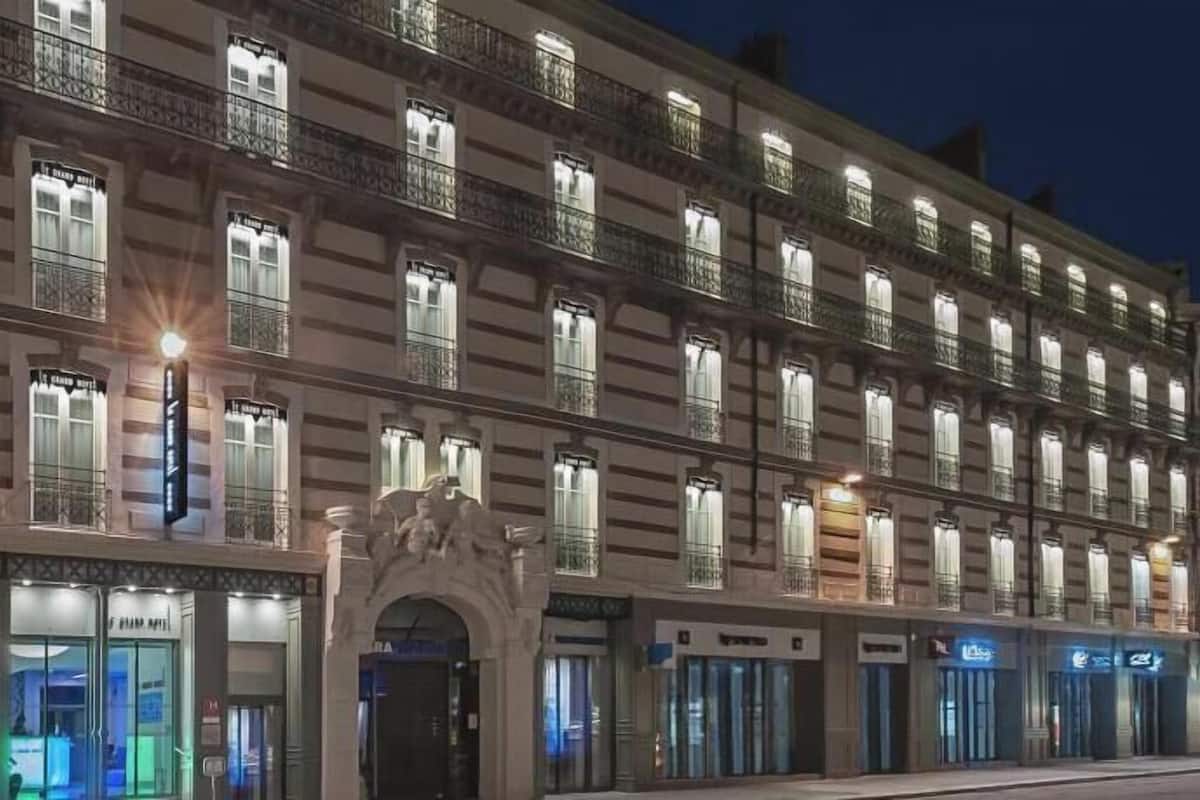 A multi-story hotel with a classic architectural style, featuring a row of balconies and large windows.