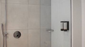A modern shower with a glass door, a handheld showerhead, and a wall-mounted control panel.