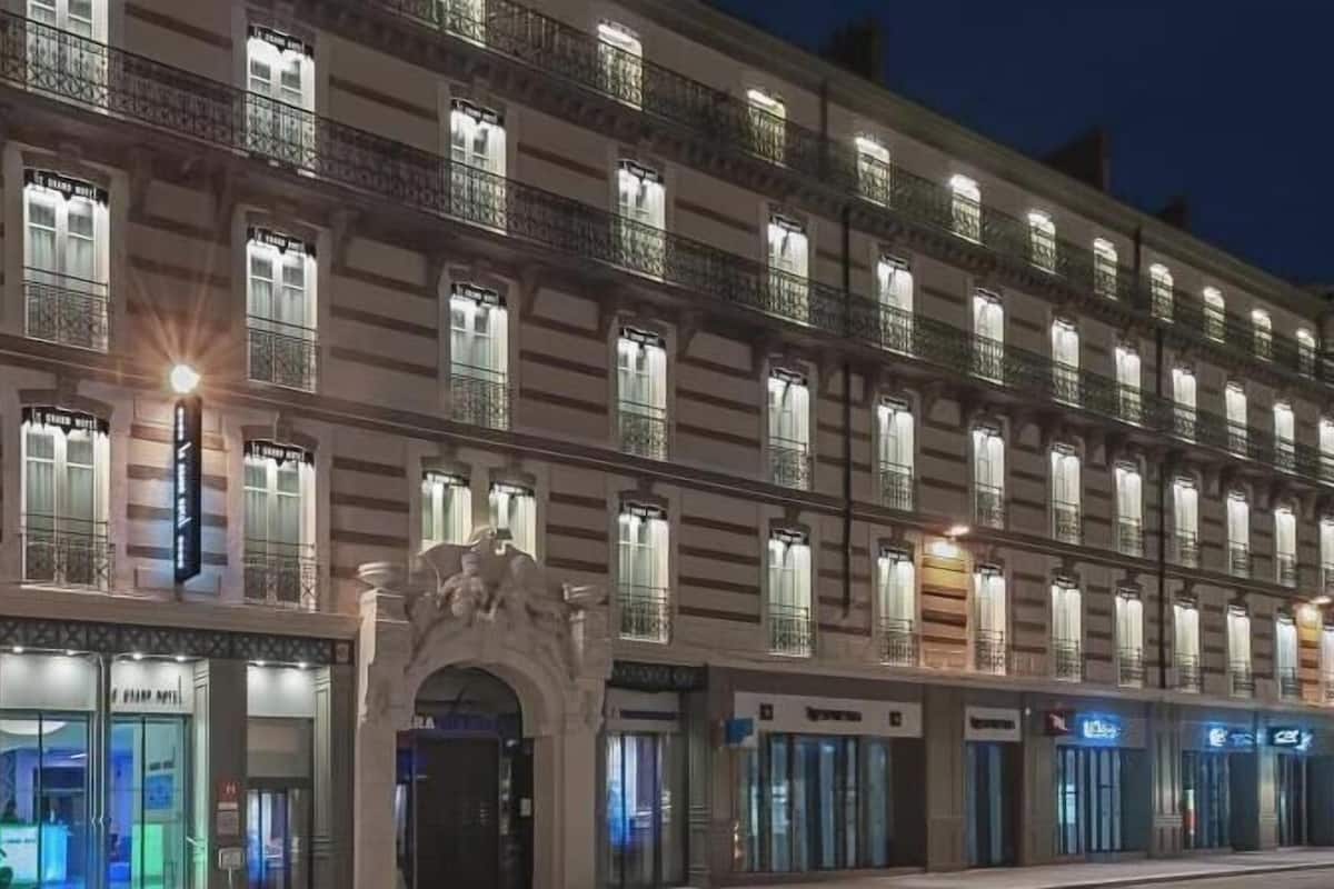 A multi-story hotel with a classic architectural style, featuring a row of balconies and large windows.