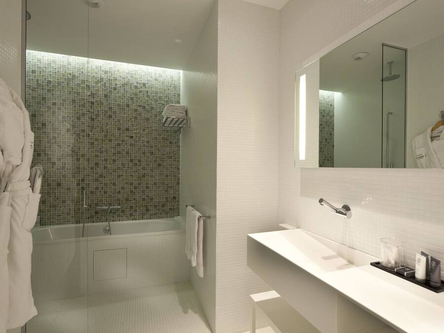 A modern bathroom with a glass-enclosed shower, a white sink, and a large mirror.