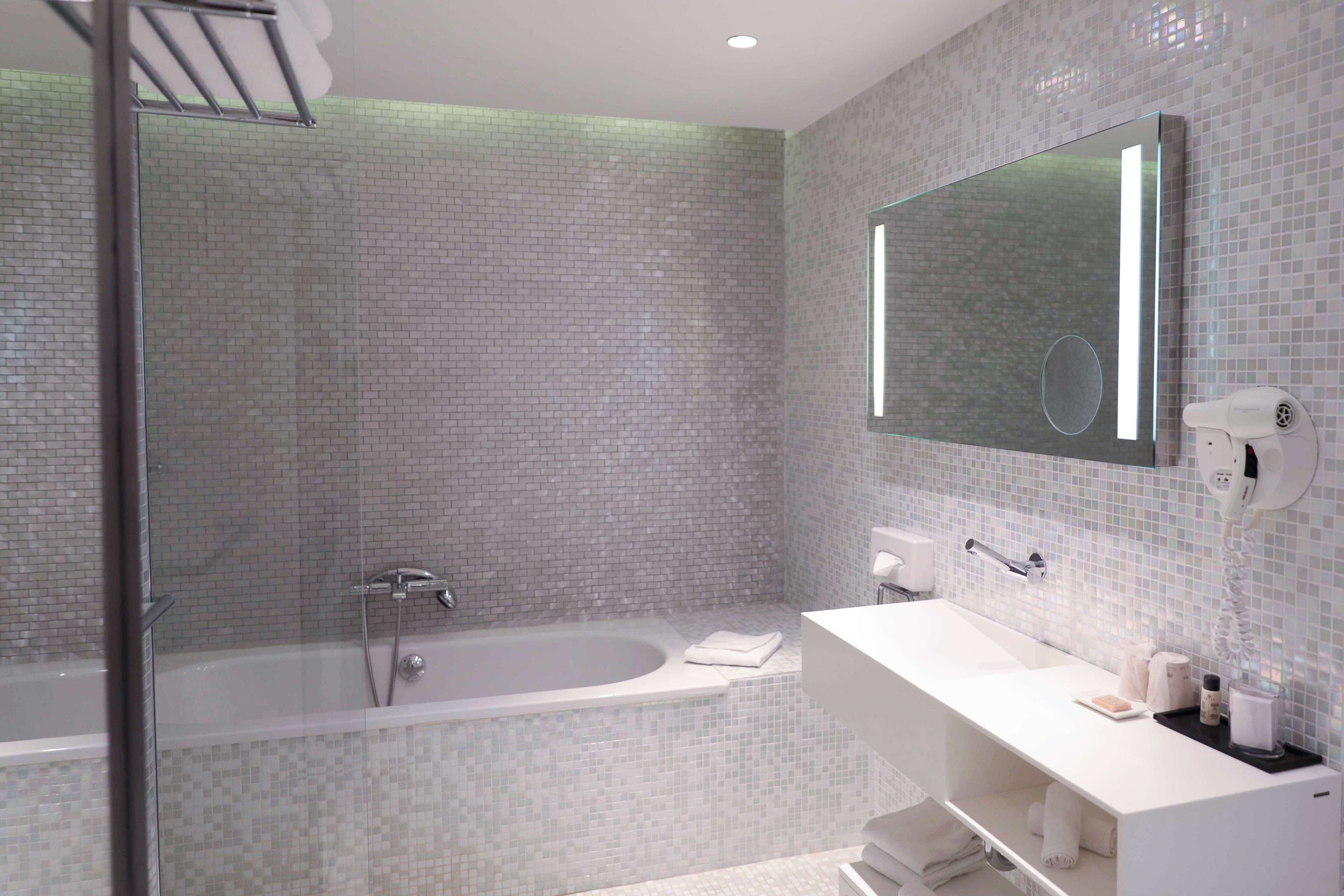 A modern bathroom with a glass shower enclosure, a freestanding bathtub, and a white vanity with a large mirror.