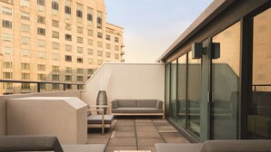 Ein moderner Balkon mit einer Couch, zwei Sesseln und einem kleinen Tisch.