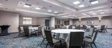 A conference room with round tables, chairs, and a carpeted floor.