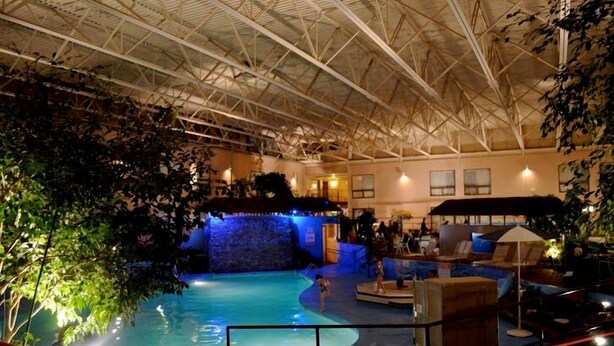An indoor swimming pool with a high ceiling and a waterfall feature. - Townhouse Hotel Grand Forks (Grand Forks)