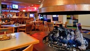 A restaurant with a large copper chimney, wooden tables, chairs, and televisions on the walls. - Townhouse Hotel Grand Forks (Grand Forks)