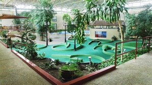An indoor garden with green pathways, potted plants, and a small building with a window. - Townhouse Hotel Grand Forks (Grand Forks)