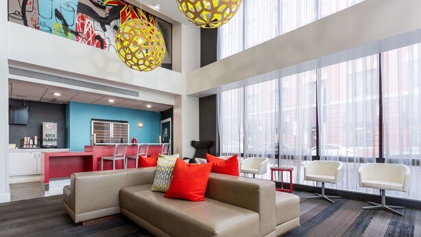 A modern living room with a beige sofa, red and yellow cushions, and a kitchen area in the background. - Comfort Inn & Suites Baltimore Inner Harbor (Baltimore)