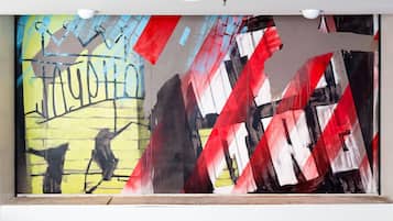 A large abstract painting with geometric shapes and bold colors on a wall.