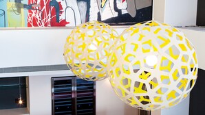 A modern interior with a red dining area, two spherical light fixtures, and a colorful abstract painting on the wall. - Comfort Inn & Suites Baltimore Inner Harbor (Baltimore)