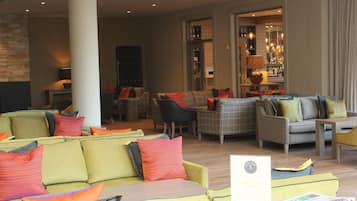 A spacious living area with multiple seating options, including sofas and armchairs, arranged around a central coffee table.