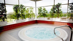 Un jacuzzi con vistas a un jardín a través de amplias ventanas.