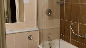 A bathroom with a glass-enclosed shower, a white bathtub, and a toilet.