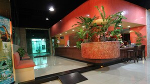 A hotel lobby with a reception desk, a large potted plant, and a seating area. - Hotel Plaza Caribe (Cancun)