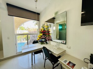 A modern kitchen with a dining table, chairs, a large mirror, and a view of a swimming pool. - Hotel Plaza Caribe (Cancun)