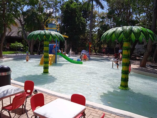 A water park with slides and water features, surrounded by trees.