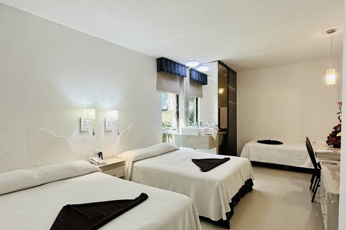 A hotel room with two beds, a desk, and a chair.