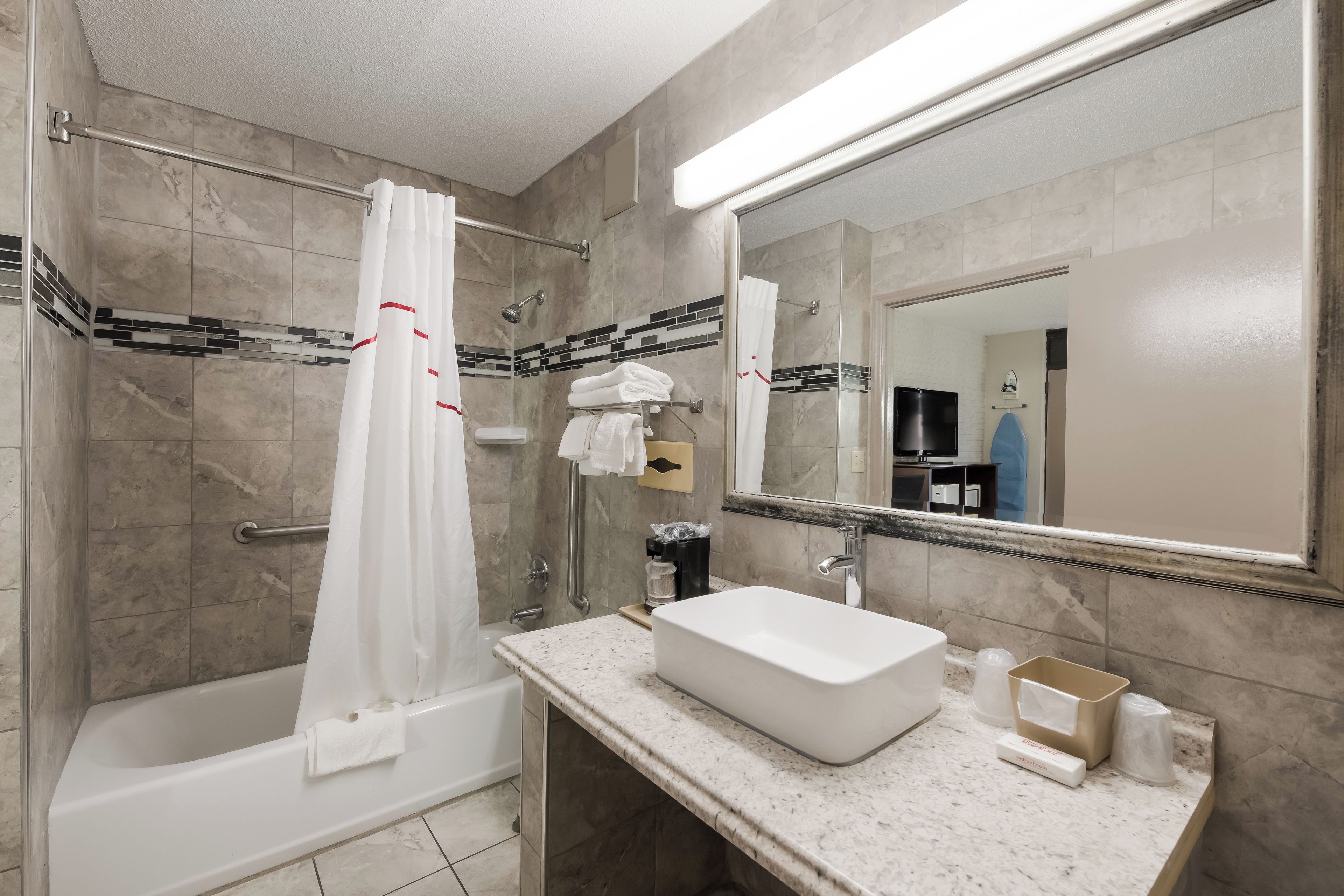 A bathroom with a bathtub, a sink, a shower, and a mirror.
