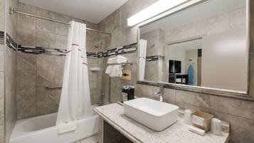 A bathroom with a bathtub, a sink, a shower, and a mirror.
