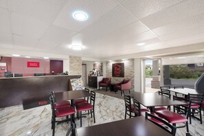 A restaurant with a marble floor, red upholstered chairs, and a counter with a 'Free Wi-Fi' sign.