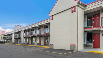 A motel with multiple rooms, a parking lot, and a clear blue sky.