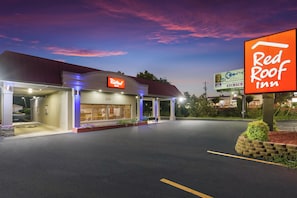 A Red Roof Inn with a well-lit entrance, a parking lot, and a clear sky.