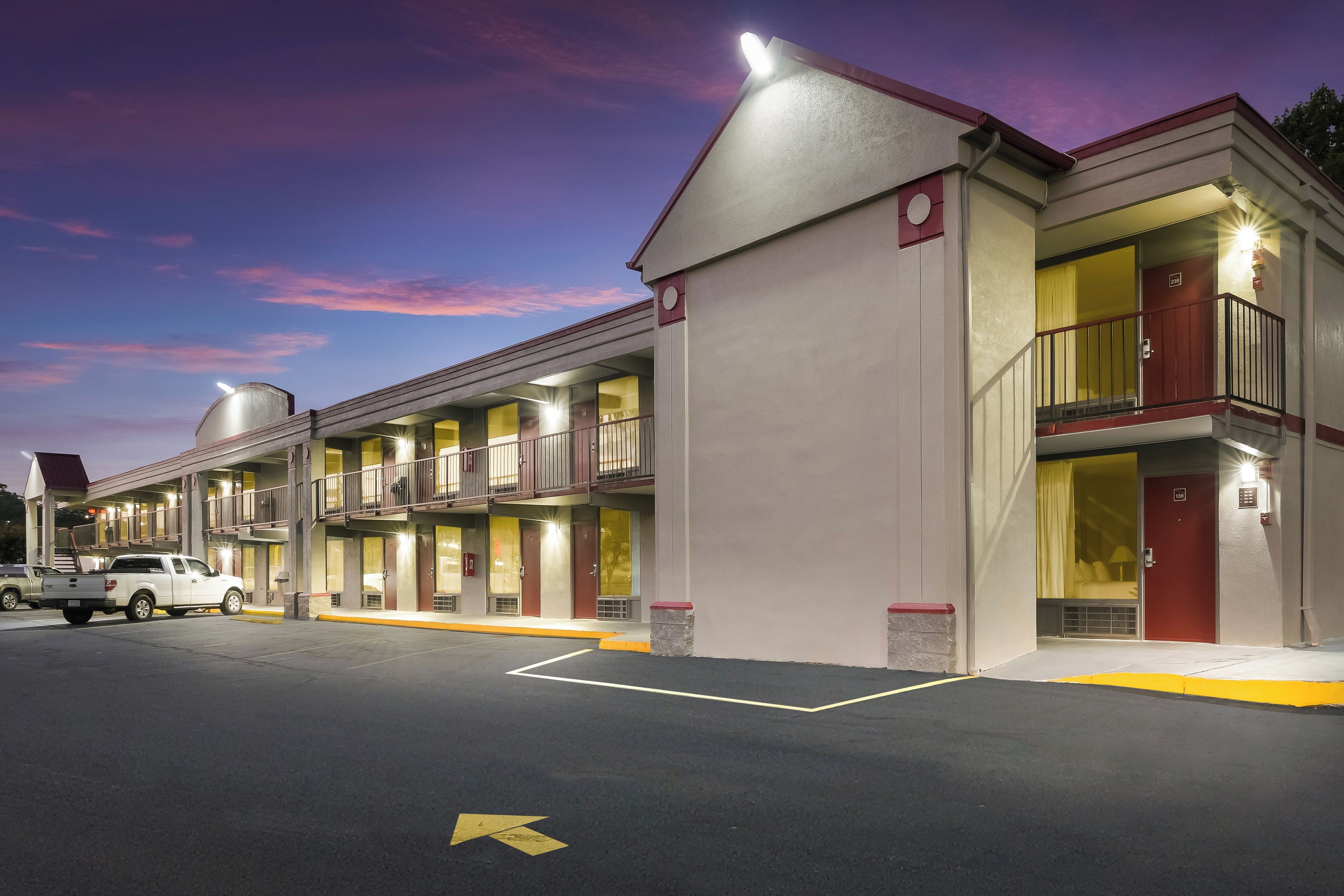 A motel with multiple rooms, a parking lot, and a clear sky.